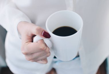 Kız siyah kahve sabah holding beyaz gömlek giymiş. Kızıl kırmızı manikür