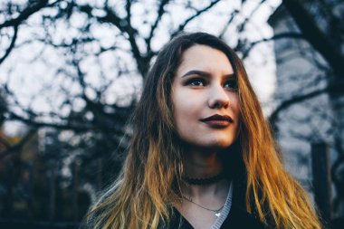 Yakın çekim yakışıklı bir uzun saçlı esmer güzel kahverengi gözleri ile bakarak. Beyaz beyaz manken duygusal bakış. Siyah arka planda bir kuru sonbahar ağaç dallarında keskin.  