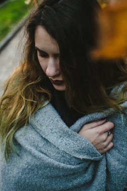 İhale esmer gri battaniye ayakta sokakta kaplı. Soğuk sonbahar kavramı. Üzgün modeli kaldırımda aşağı bakıyor.