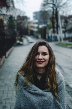 Genç Beyaz modeli ayakta kaldırımda gülümseyerek. Sonbahar yağmur sonra mavi ıslak asfalt. Erken akşam. Kentsel kavramı