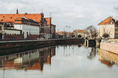 Bir güneşli bahar gününde Cityscape Wroclaw. Gri-mavi gökyüzü ve kırmızı çatılar ile eski klasik binalar yansıtan oder nehrinin su. 