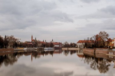 Binalar, ağaçlar ve gri gökyüzü sakin rüya gibi görünümünü oder Nehri Wroclaw, Polonya için kristal berraklığında su yansıtılır. Bir arka plan üzerinde kırmızı çatılar ile tipik binalar