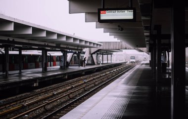 Amsterdam'da neredeyse boş metro istasyonundan tren geliyor. Gölgeli platform gri soğuk bir sabah sis ile kaplı. Melankolik kentsel kavram. 