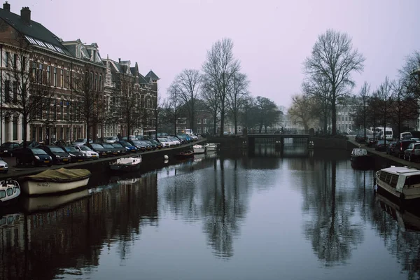 Haarlem, Holandia-5 lutego 2019: Cityscape Beautifil miasta w Holandii. Kamienny most łączący dwa brzegi rzeki Spaarne. Suche drzewa wiosna rzucają cienie nad gładką wodą w kanale. — Zdjęcie stockowe