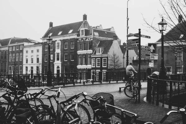Літній чоловік їхав на велосипеді і перетинаючи міст в Гарлемі, Нідерланди. Велосипедист їде біля Велопарковки. Старовинні чорно-білі кольори. — стокове фото