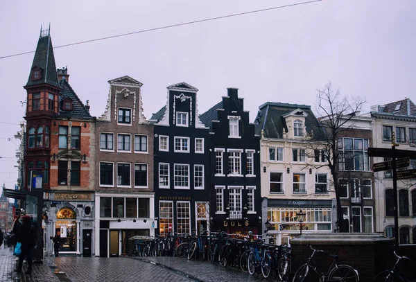 Casas holandesas de tijolos tradicionais em Amsterdã, Holanda. Paredes de fachada preta e pastel estreitas com janelas altas contra o céu cinzento nublado . — Fotografia de Stock