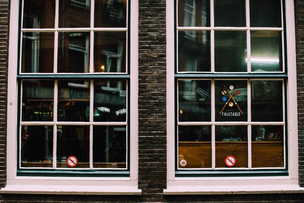 Ámsterdam, Países Bajos - 6 de febrero de 2019: Ventanas de un antiguo pub "Café Mooy" situado en la parte central de la ciudad. Reflejos coloridos e interiores tradicionales vistos a través del cristal de la ventana — Foto de Stock