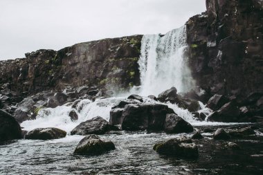 Thingvellir Milli Parkı Oxararfoss şelale, İzlanda kayalarla dolu havuza nehirden akan. İlkbaharda soğuk bulutlu hava