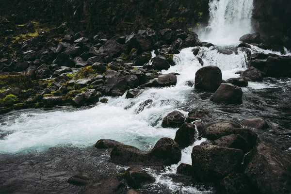 Водопад ксаррфосс в Национальном парке Тингвеллир, Исландия, впадающий в бассейн, наполненный камнями. Холодная облачность весной — стоковое фото