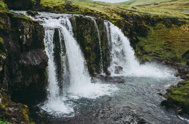 İzlanda'daki Kirkjufell şelalesi. Berrak su akıntıya düşüyor. Soğuk gri bir öğleden sonra güzel sahne.