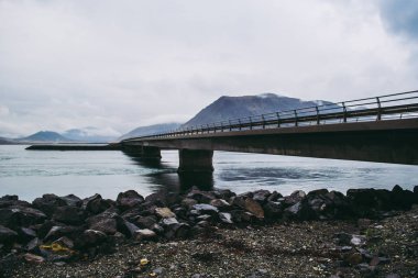 İzlanda'da dağ gölü üzerinde beton köprü. Soluk mavi tonları