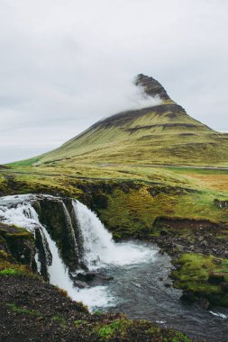 Kirkjufellsfoss şelale ve dağ ünlü görünümü. İzlanda'da görülecek ve deneyimlenen en unutulmaz manzaralardan biri.