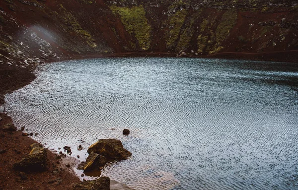 Agua azul oscura del lago Kerid ubicada dentro del cráter volcánico en el sur de Islandia. Gotas de lluvia y pequeñas olas causadas por el viento en toda la superficie del lago —  Fotos de Stock