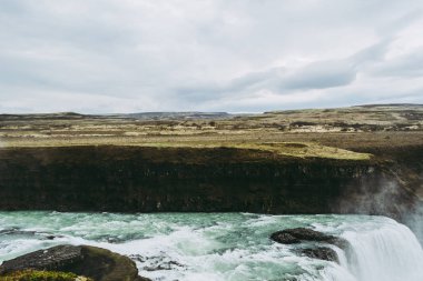Güneybatı İzlanda Gullfoss şelale yatay görünümü. Üzerinde soluk beyaz sıçramaları ile mavi ve yeşil su. İzlanda manzaraları.