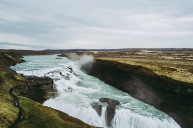 İzlanda'da Gullfoss'un parlak beyaz suları. Manzaraya hayran olan turist grupları
