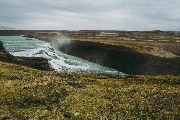 굴포스( Gullfoss) - 아이슬란드에서 가장 아름다운 여행지 중 하나입니다. 청록색 물이 있는 옅은 녹색 잔디와 폭포. — 스톡 사진