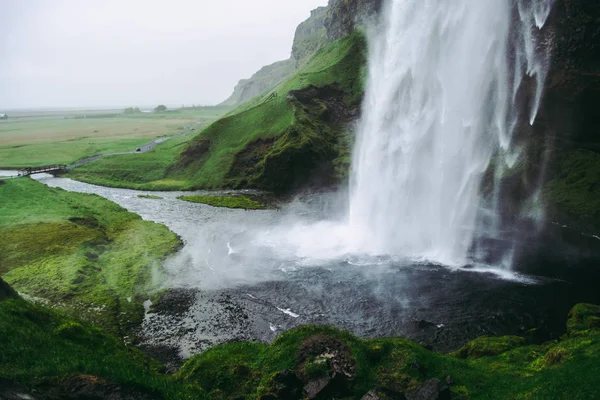 Agua blanca pálida fría de la cascada Seljalandsfoss en Islandia. Clima ventoso típico . — Foto de Stock