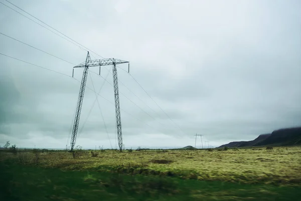 Redes eléctricas en el campo por la carretera. Vista borrosa a través de la ventana. Nubes grises pesadas —  Fotos de Stock