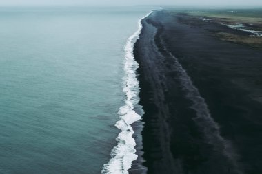 Turkuaz su, beyaz köpük ve siyah kum. Vik, İzlanda'da büyülü ve sakin atmosophere.