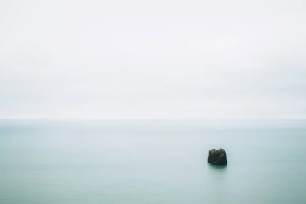 Água azul-turquesa suave do oceano Atlântico e um pequeno pedaço de rocha nele. Calma e minimalismo. Islândia do Sul — Fotografia de Stock