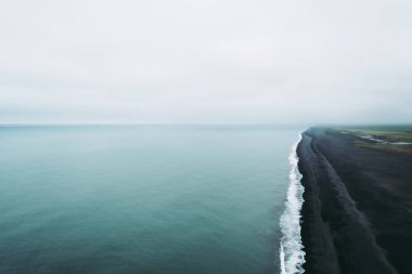 Siyah kum plaj üzerinde Dyrholaey lightouse uçurumun atmosferik görünümü. İzlanda manzaraları