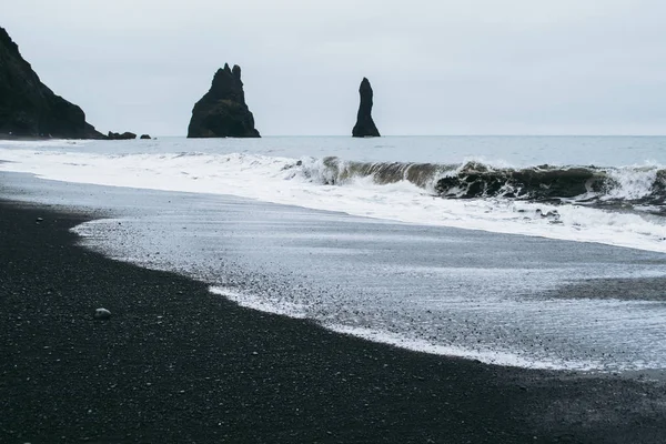 Famoso panorama della spiaggia di sabbia nera in Islanda. Onde oscure di onde oceaniche atlantiche che coprono la sabbia Fotografia Stock