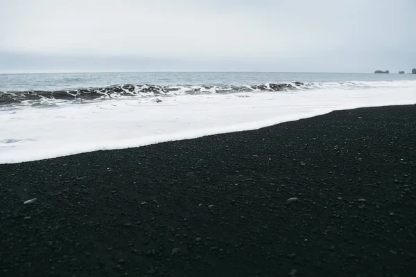 Desaturated Icelandic landscapes. Ocean water, black sand, and gray sky