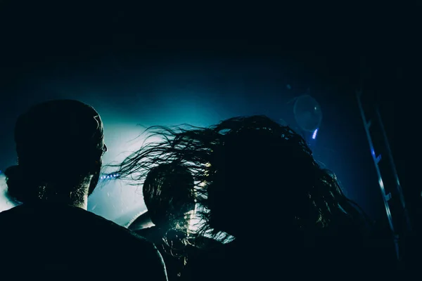 A metalhead Headbanging során a show. Szál haj mély kék és sárga színpadi fények. — Stock Fotó