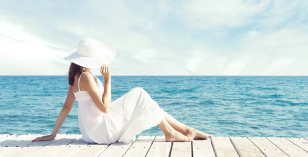 美丽的 迷人的和年轻的女孩坐在白色的礼服在码头上 度假和旅游概念 — 图库照片