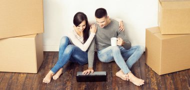 Erkek ve kadın dizüstü pc ve bir kutu içeren. Genç bir çift bir dizüstü bilgisayar ile enterne browsing. Yeni bir ev kavram taşıma.