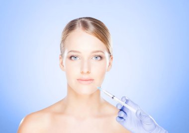 Genç bir kadının güzel yüzüne iğne yapan bir doktor. Estetik ameliyat konsepti.