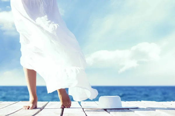 Mooie voeten van een vrouw in witte jurk op een houten pier. — Stockfoto