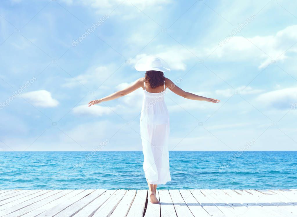 Young beautiful woman standing on a pier at summer.  Vacation, traveling and tourism concept.