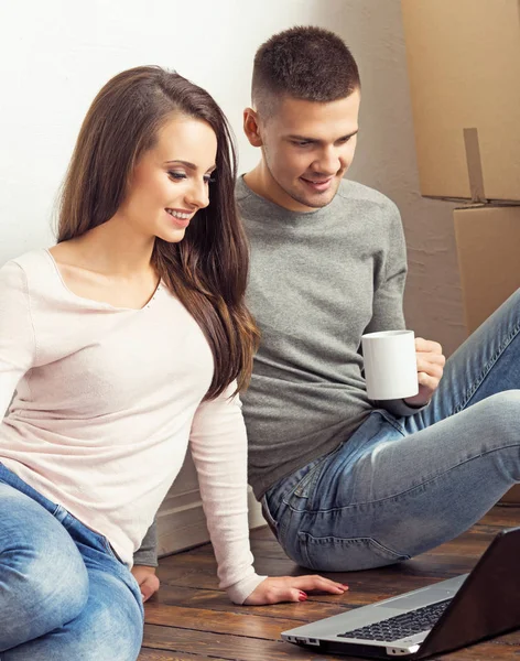 男人和女人用笔记本电脑和一个盒子 年轻夫妇用手提电脑浏览互联网 在一个新的家庭概念中移动 — 图库照片