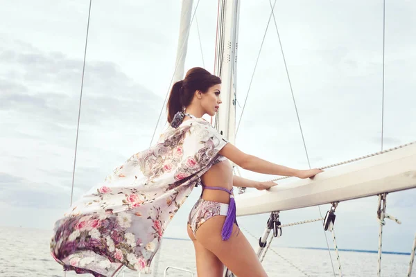 Beautiful and sexy fashion model posing on a sailing boat in swimsuit.