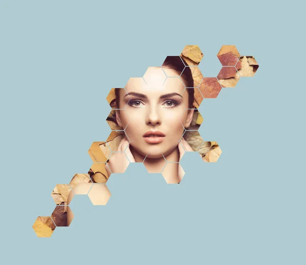 Beautiful face of young, natural and healthy girl over fallen leaves. Healthcare, spa, makeup and face lifting concept with honeycomb grid over autumn background.