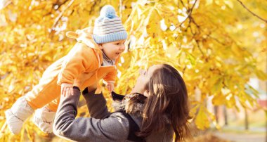 Park toddler bebek ile oynarken annesi. Anne ve oğlu mevsim sonbahar arka plan üzerinde. Aşk ve Aile kavramı.