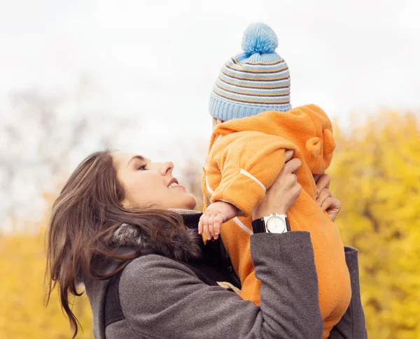 La mamma gioca al parco con il suo bambino. Mamma e figlio su sfondo autunno stagionale . — Foto Stock