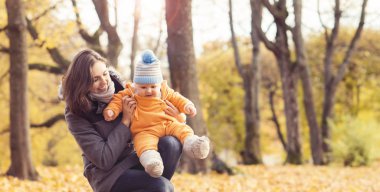 Park toddler bebek ile oynarken annesi. Anne ve oğlu mevsim sonbahar arka plan üzerinde. Aşk ve Aile kavramı.