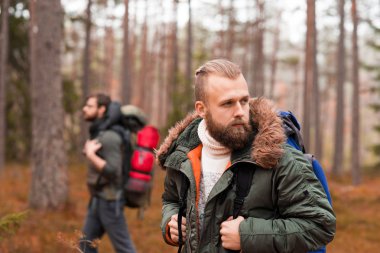 Bir sırt çantası ve arkadaşı ormanda hiking sakallı olan adam. Kamp, macera, kavram seyahat.