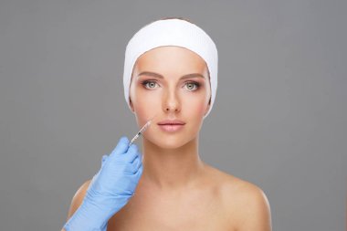 Genç bir kadının güzel yüzüne iğne yapan bir doktor. Estetik ameliyat, cilt gerdirme ve estetik tıp konsepti.