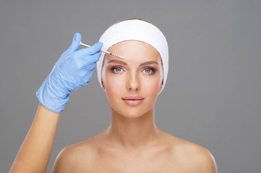 Genç bir kadının güzel yüzüne iğne yapan bir doktor. Estetik ameliyat, cilt gerdirme ve estetik tıp konsepti.