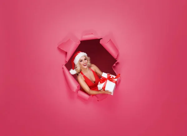 若いとサンタ帽子で美しい少女 クリスマス コンセプトの女性 紙に穴が開いて赤 Backhround — ストック写真