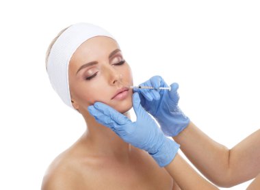 Genç bir kadının güzel yüzüne iğne yapan bir doktor. Estetik ameliyat, cilt gerdirme ve estetik tıp konsepti.