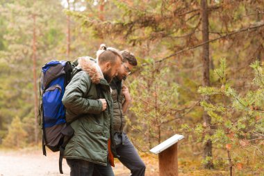 Ormanda hiking sırt çantaları ile iki sakallı adam. Kamp, macera, seyahat ve balık tutma kavramı.