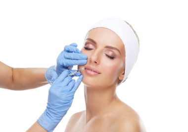 Genç bir kadının güzel yüzüne iğne yapan bir doktor. Estetik ameliyat, cilt gerdirme ve estetik tıp konsepti.