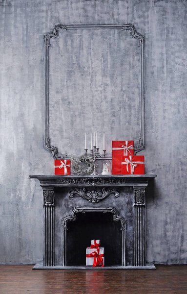 Christmas background. Ancient fireplace with a candlestick and gift boxes.