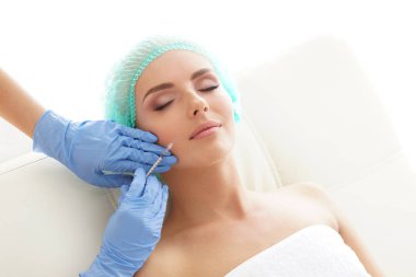 Genç bir kadının güzel yüzüne iğne yapan bir doktor. Estetik ameliyat, cilt gerdirme ve estetik tıp konsepti.