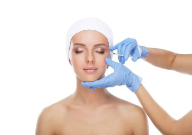 Genç bir kadının güzel yüzüne iğne yapan bir doktor. Estetik ameliyat, cilt gerdirme ve estetik tıp konsepti.