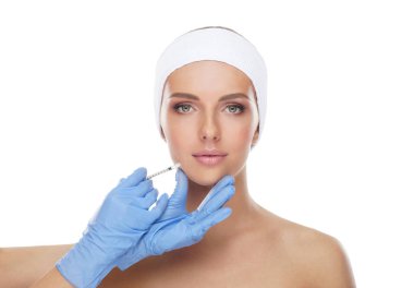 Genç bir kadının güzel yüzüne iğne yapan bir doktor. Estetik ameliyat, cilt gerdirme ve estetik tıp konsepti.